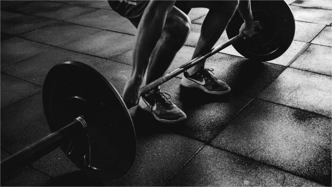 Une personne soulève une barre dans une salle de sport, illustrant l'engagement envers le conditionnement physique.